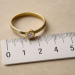 A person measuring ring size at home with a ruler and string